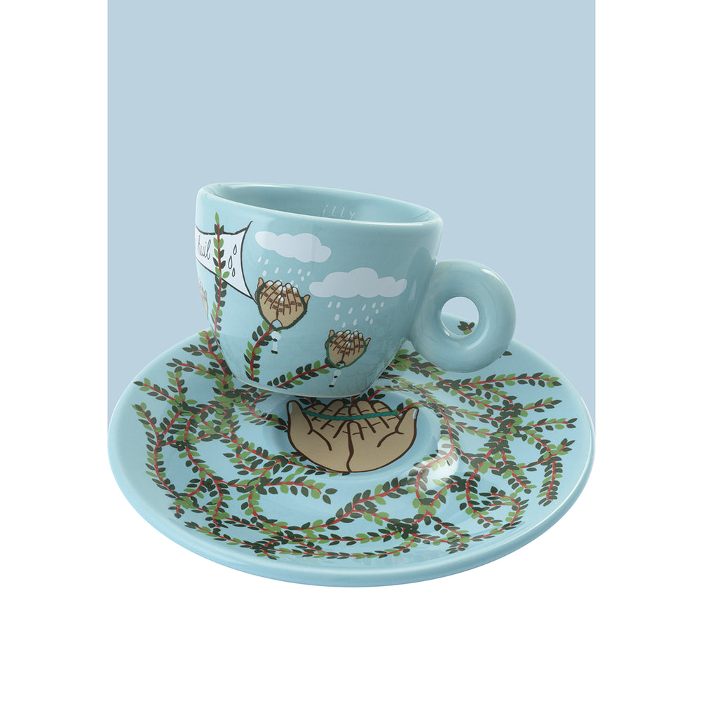 A light blue ceramic espresso cup and matching saucer set, decorated with a whimsical illustration of thistle flowers, rain, and a broken cup on a branch.
